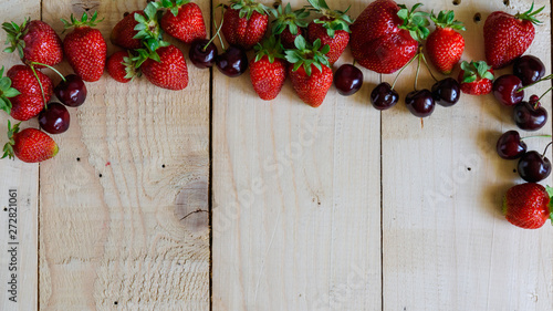 strawberries and cherries on a wooden background