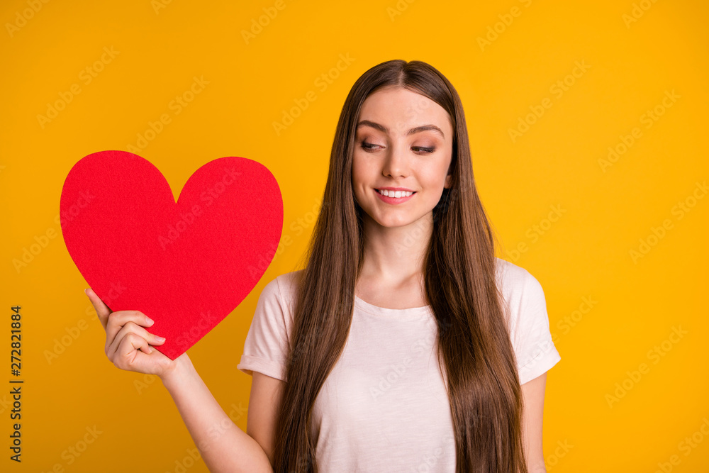Close up photo beautiful she her lady very long hair hold hand arm large paper heart postcard invitation date prom look interested curious cunning wear casual t-shirt isolated yellow background Close up photo beautiful she her lady very long hair hold hand arm large paper heart postcard invitation date prom look interested curious cunning wear casual t-shirt isolated yellow background