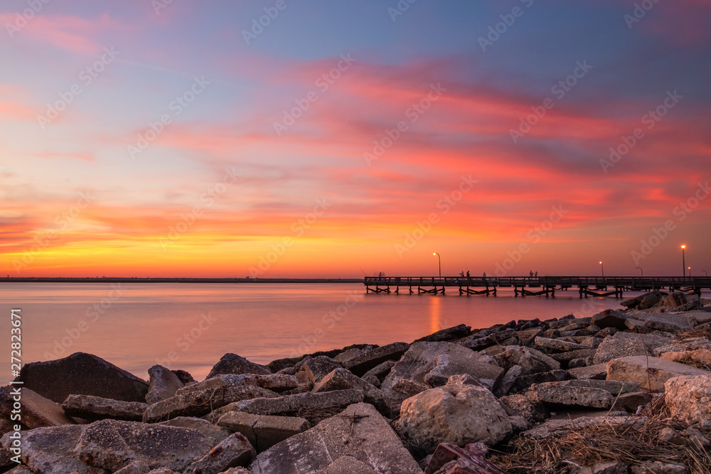 Vibrant pink and orange sunset over a fishing pier and rock jetty. Jones Beach New York. Vibrant pink and orange sunset over a fishing pier and rock jetty. Jones Beach New York.