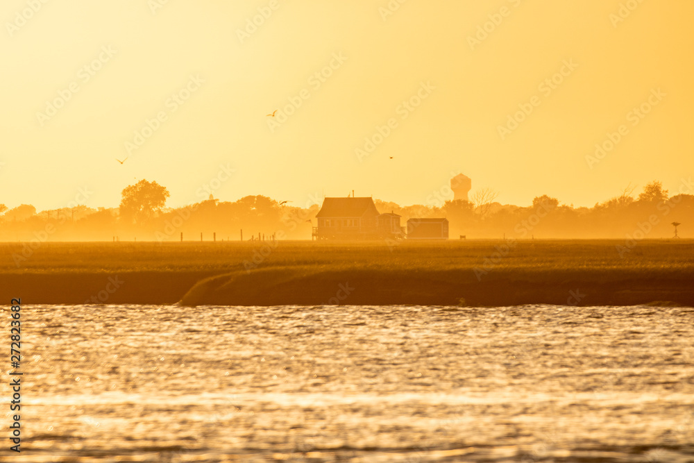 Golden light shining on a small bay house on the water at sunset. Long Island New York. 