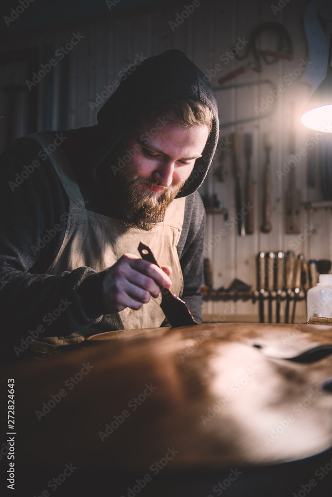 Obraz premium Young luthier working in his workshop, building a double bass