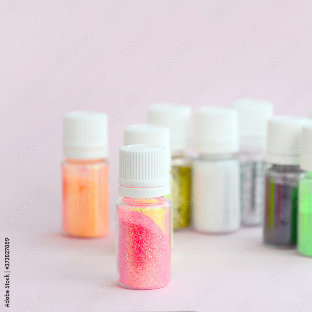 Colorful glitters lies on pastel pink background. Many round jars with multi-colored bright sparkles for nail polish. Sparkling sequins Colorful glitters lies on pastel pink background. Many round jars with multi-colored bright sparkles for nail polish. Sparkling sequins