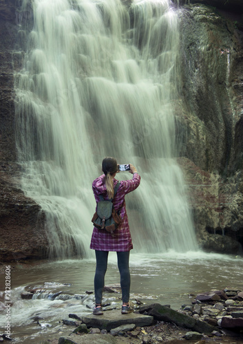Girl photographs a waterfall with a phone