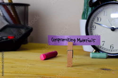 Compromising Materials. Handwriting on sticky notes in clothes pegs on wooden office desk photo