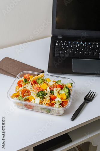Healthy food in lunch box, on working table with laptop