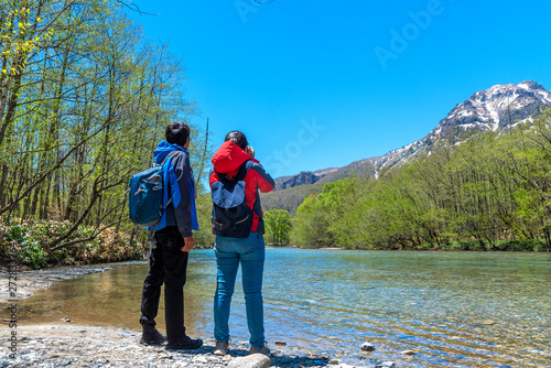 Man and woman with Azusa river and Mount Yake on background at Kamikochi in Northern Japan Alps.