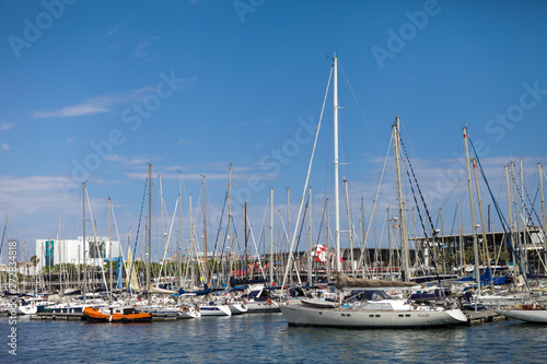 Barcelona old port with yachts and boats. Blue sky and mast s on foreground. Travel and vacations  Spanish port. Mediterranean sea. Summer sunny day.