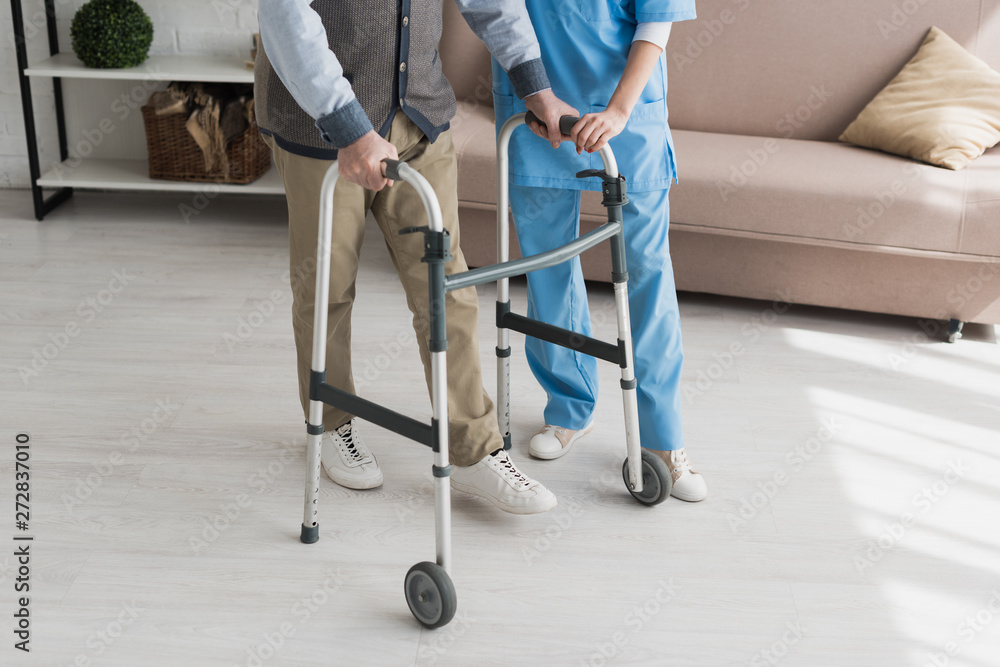 Senior man walking with nurse, and recovering from injury - obrazy, fototapety, plakaty 