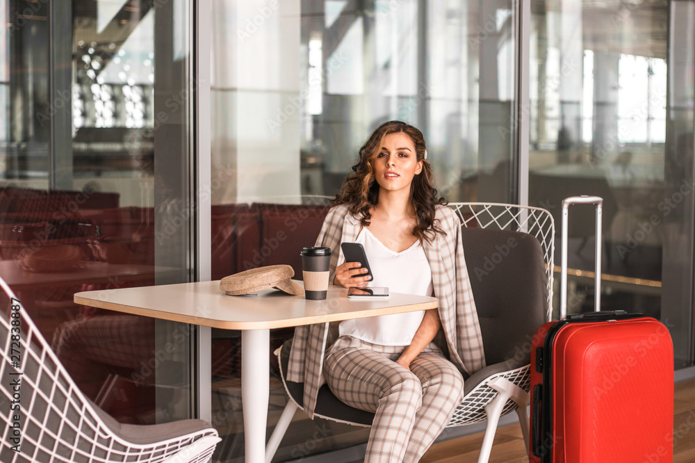 Beautiful business woman with smartphone waiting for her flight in an airport.