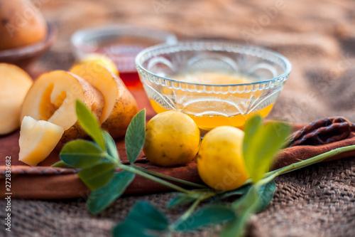 Glowing face mask of potato juice in a glass bowl on brown colored surface along with some lemon juice,potato juice and honey.Horizontal shot. photo