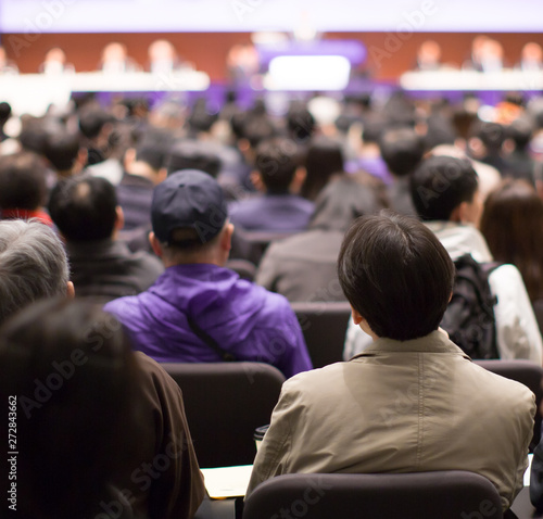 Seminar presenter at corporate conference giving speech. Speaker giving lecture to business audience. Executive manager leading discussion in hall during company training event. 