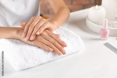 Woman showing neat manicure at table, closeup with space for text. Spa treatment