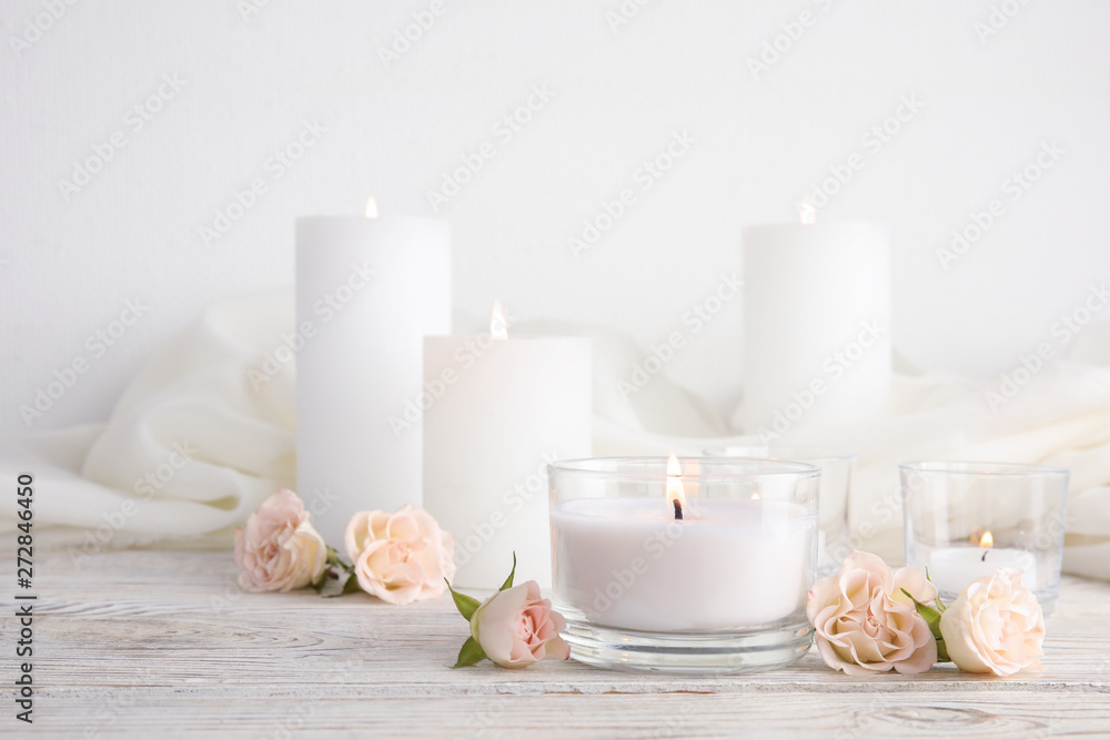 Composition with burning aromatic candles and roses on wooden table. Space for text - obrazy, fototapety, plakaty 
