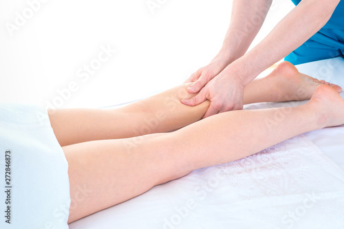 Detail of hands massaging human calf muscle.Therapist applying pressure on female leg