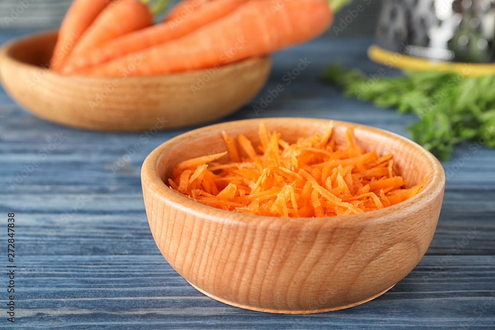 Bowl of grated carrot on wooden table, closeup Bowl of grated carrot on wooden table, closeup