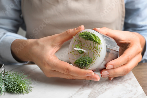 Woman making conifer candle at table, closeup