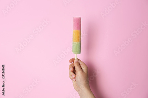 Woman holding delicious ice cream against color background