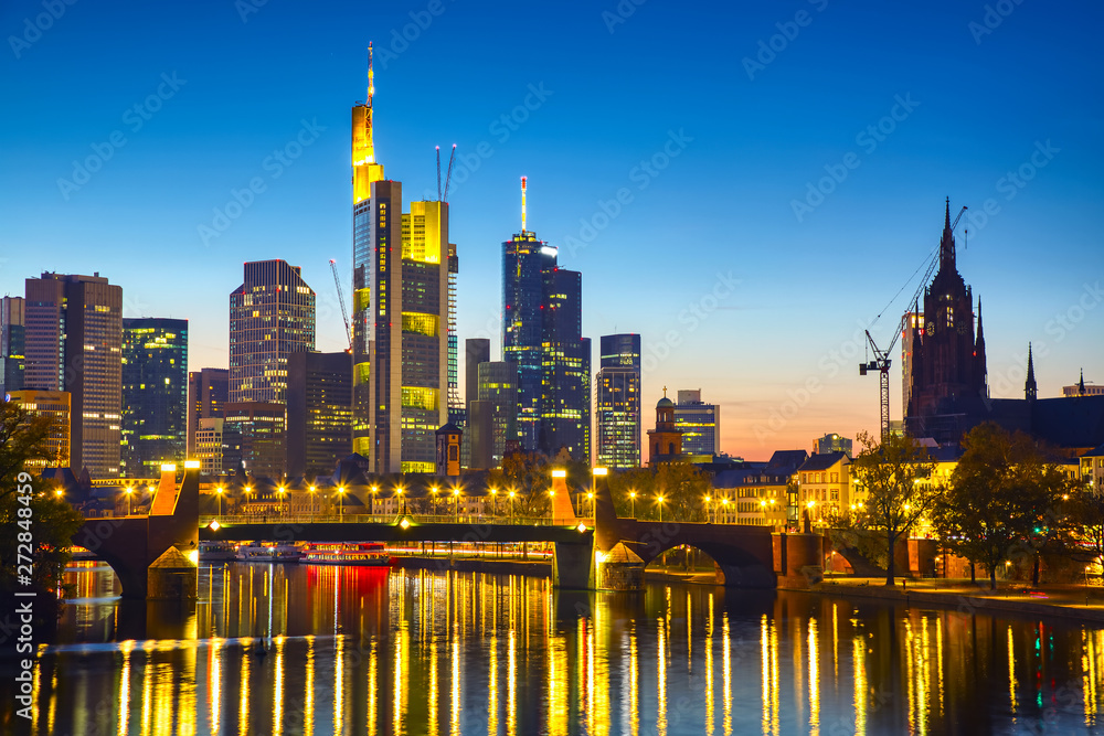Obraz premium Panoramic view cityscape skyline of business district with skyscrapers and mirror reflections in the river Main during sunset blue hour, Frankfurt am Main. Hessen, Germany