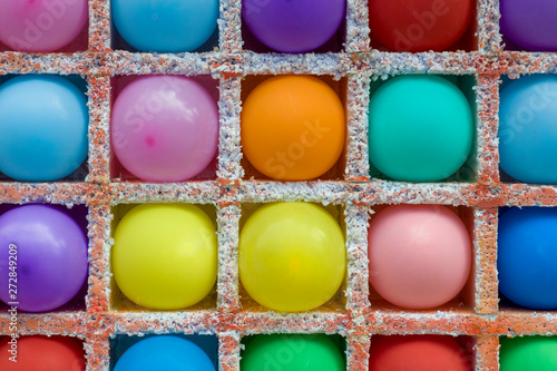 bright multi-colored round balloons in square niches from styrofoam close up in a dash. rough surface texture
