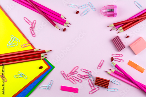 Paper of different colors, stationery of pink and red color lie on a pink background.