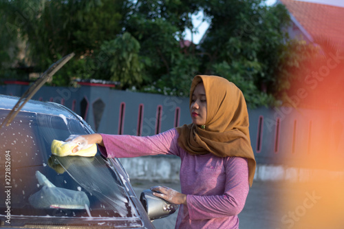 hijab woman cleaning the windshield at outdoors area