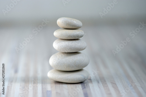Harmony and balance, cairns, simple poise pebbles on wooden light white gray background, simplicity rock zen sculpture