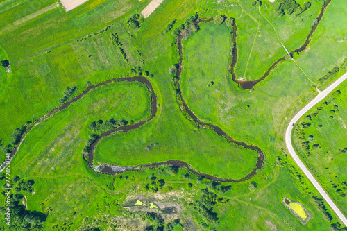 Aerial landscape countryside of winding small river, stream in green field, top view meadow.