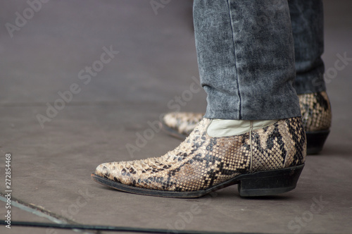 closeup of man feet with snake american boots at country show in outdoor