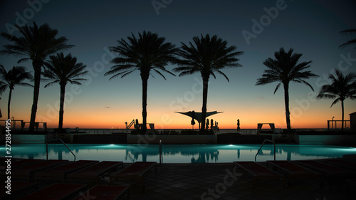 SILHOUETTE OF PALM TREES AT A POOL DECK DURING SUNRISE © blink2click