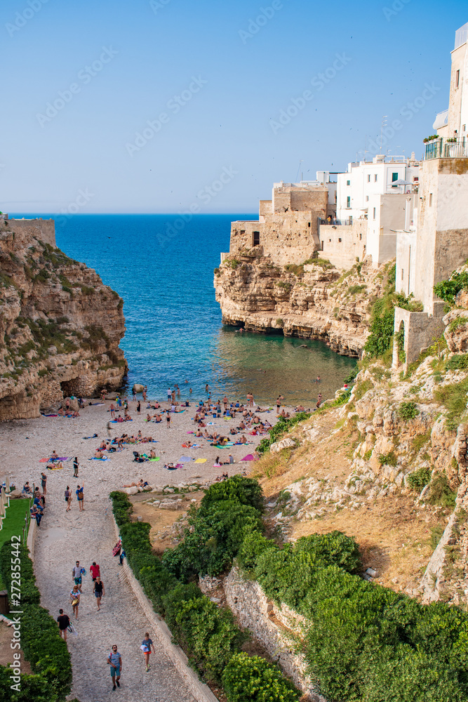 Panoramic city skyline with white houses and beach, town on the rocks, Puglia region, Italy, Europe. Traveling concept background with blue sea, vertical