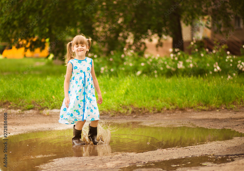 Little kid girl runs through a puddle. summer outdoor Little kid girl runs through a puddle. summer outdoor