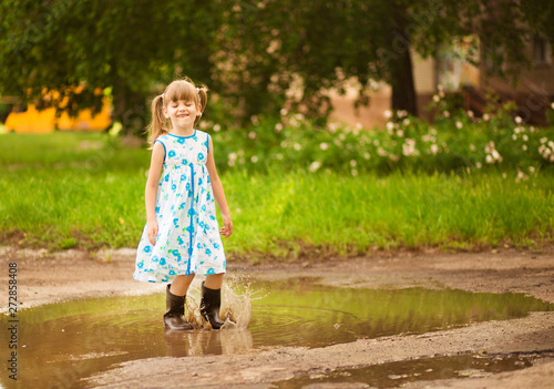 Little kid girl runs through a puddle. summer outdoor