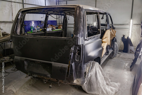 Canvas Print A large black matte car without windows is covered in paper and adhesive tape to