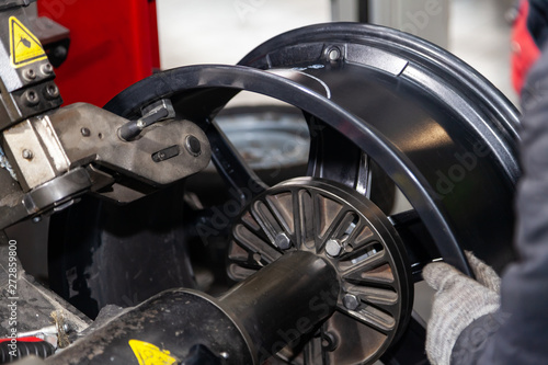 Tableau sur toile The process of repairing an automobile wheel using a special press on a machine for straightening disks for vehicles after damage in a pit on the road in the workshop