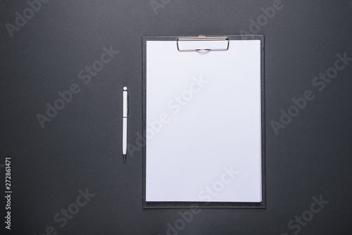 Business concept design tablet with white sheet of paper and pen on black background with copy space