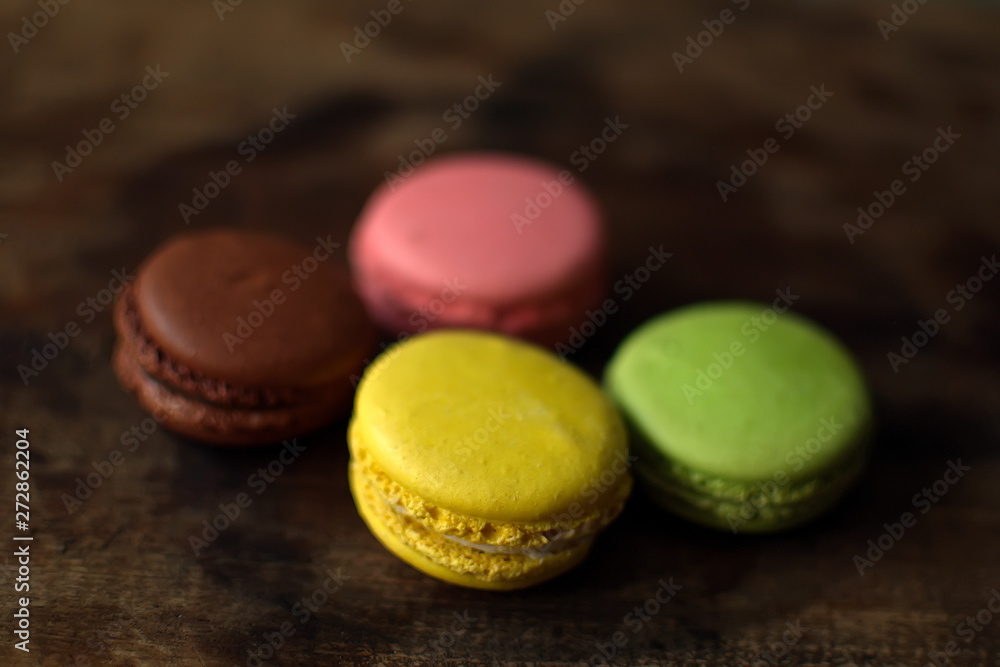 Multi-colored macaroons on a wooden tray. Pink, yellow and green macaroon. Multi-colored macaroons on a wooden tray. Pink, yellow and green macaroon.