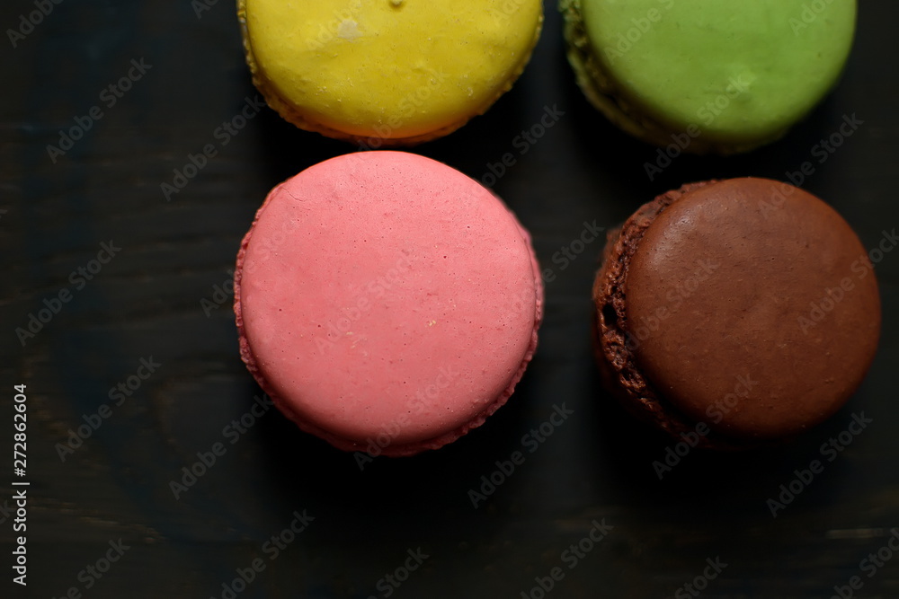 Multi-colored macaroons on a wooden tray. Pink, yellow and green macaroon. Multi-colored macaroons on a wooden tray. Pink, yellow and green macaroon.