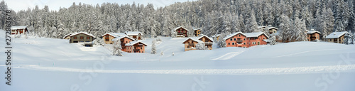 Wall Mural Winter panorama of the snowy landscape at the evening with forest and cosy buildings in Surlej village in Switzerland