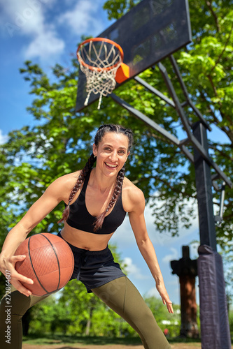 Beautiful sexy fitness girl in black sport wear with perfect body with basket ball at basketball court. Sport, fitness, lifestyle concept