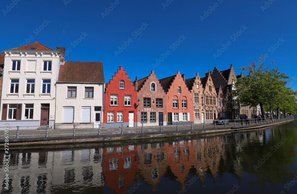Scenic city view of Bruges canal with beautiful medieval colored houses, bridge and reflections at sunny day.