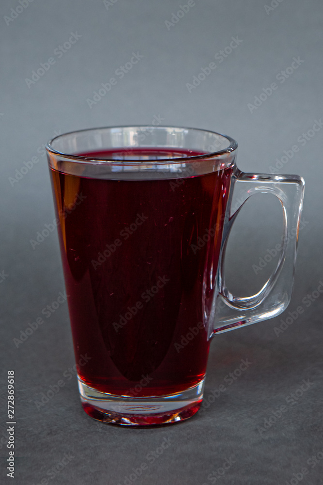 a transparent mug with a handle filled with hot bright tea of intense color on a dark gray background, the photo is suitable for the menu of cold tea in the cafe a transparent mug with a handle filled with hot bright tea of intense color on a dark gray background, the photo is suitable for the menu of cold tea in the cafe