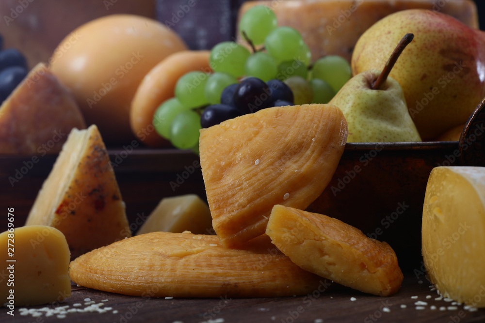 Still-life from firm grades of cheese and fruit on a black background. Side view. The concept of still life or illustration. Still-life from firm grades of cheese and fruit on a black background. Side view. The concept of still life or illustration.