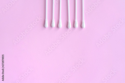 Row of white clean cotton swabs with selective focus on pink neutral background with empty space for text. Personal hygienic cotton buds for daily routine. Soft cotton ear sticks. Healthcare tools 