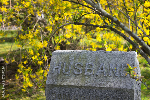 gravestone with Husband on it with flower background. Concept of lost of spouse, widowness, getting old alone