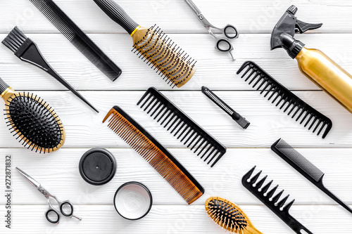 Combs, sciccors and hairdresser tools in beauty salon work desk on white wooden background top view pattern