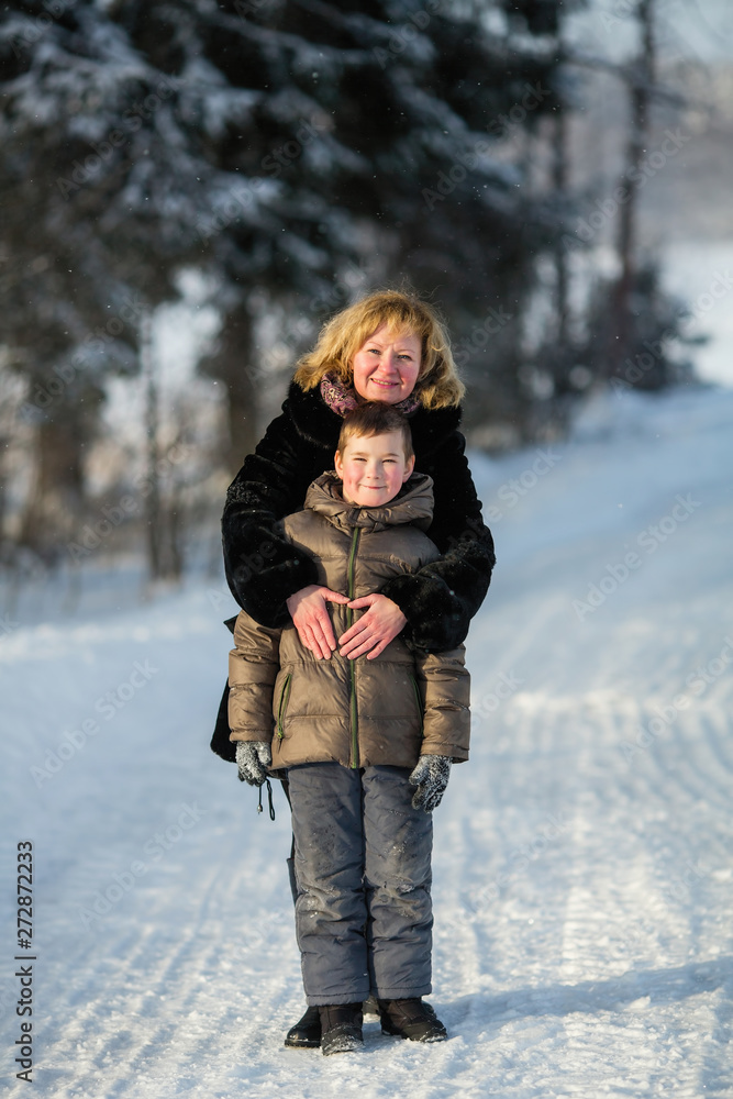 Young woman playing with a little boy in a snowy winter Park. Young woman playing with a little boy in a snowy winter Park.