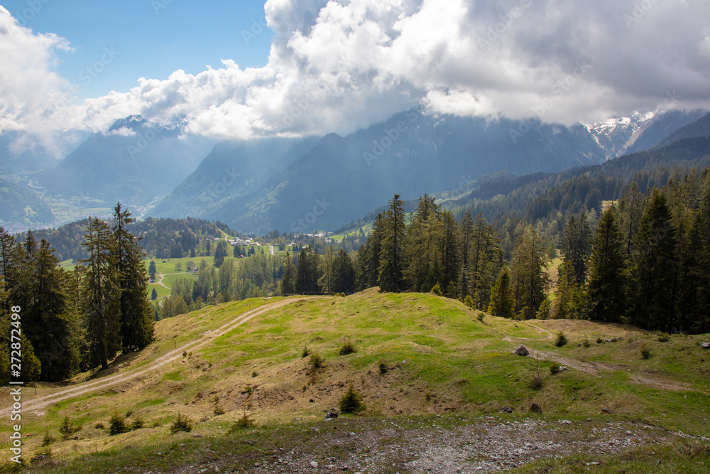 Panorama of an alpine landscape with high mountains, green meadows and trees in spring with snow in Austrian Alps Panorama of an alpine landscape with high mountains, green meadows and trees in spring with snow in Austrian Alps