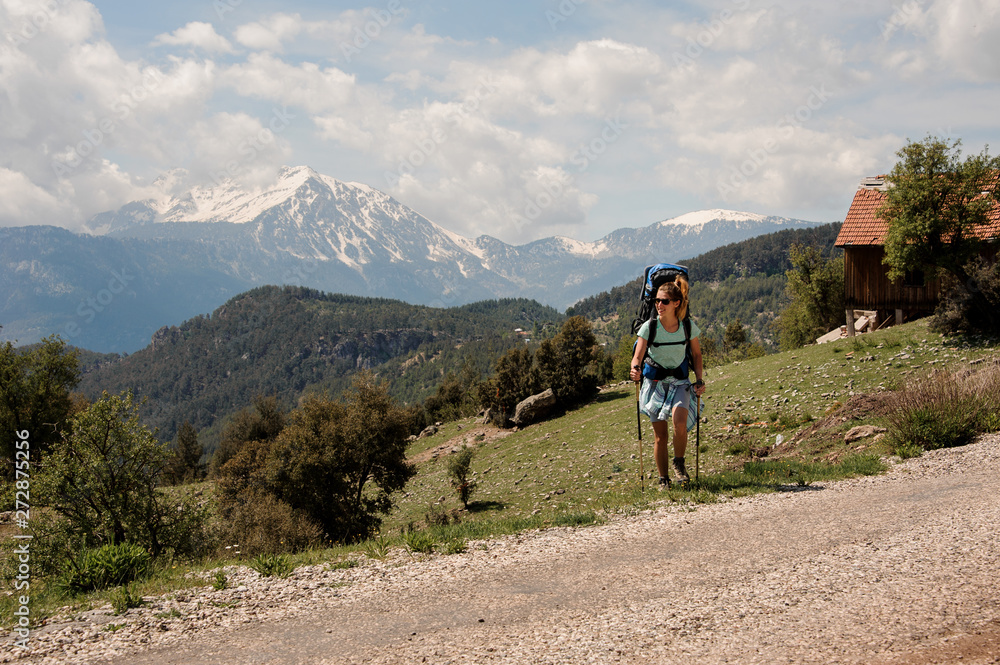 Female hiker travels near road in hills