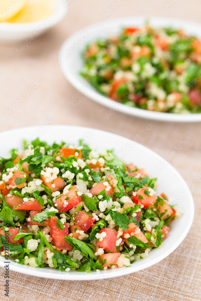 Fresh vegan Tabbouleh salad made of tomato, parsley, onion and couscous on plates (Selective Focus, Focus one third into the salad) Fresh vegan Tabbouleh salad made of tomato, parsley, onion and couscous on plates (Selective Focus, Focus one third into the salad)