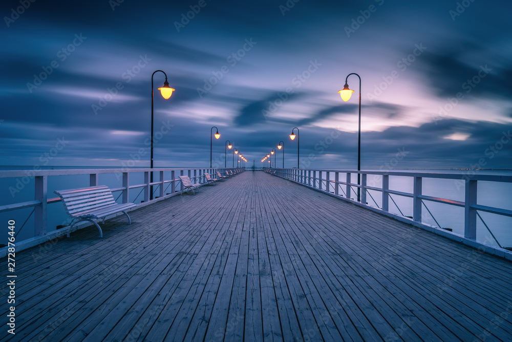 Illuminated wooden pier in Gdynia Orlowo. Early morning on the Baltic Sea. Poland, Europe.